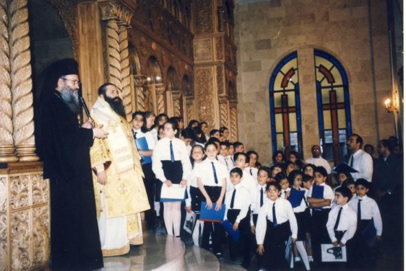 Mitropolitul Nafpaktosului, Ierótheos, vorbește în Sfânta Biserică a Prorocului Ilie din Alep. Se distinge și Mitropolitul Pavel, precum și corul de copii al bisericii (2001).